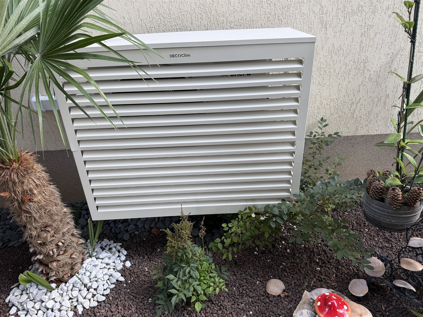Groupe extérieur dissimulé derrière un cache-climatisation à lames, dans un jardin