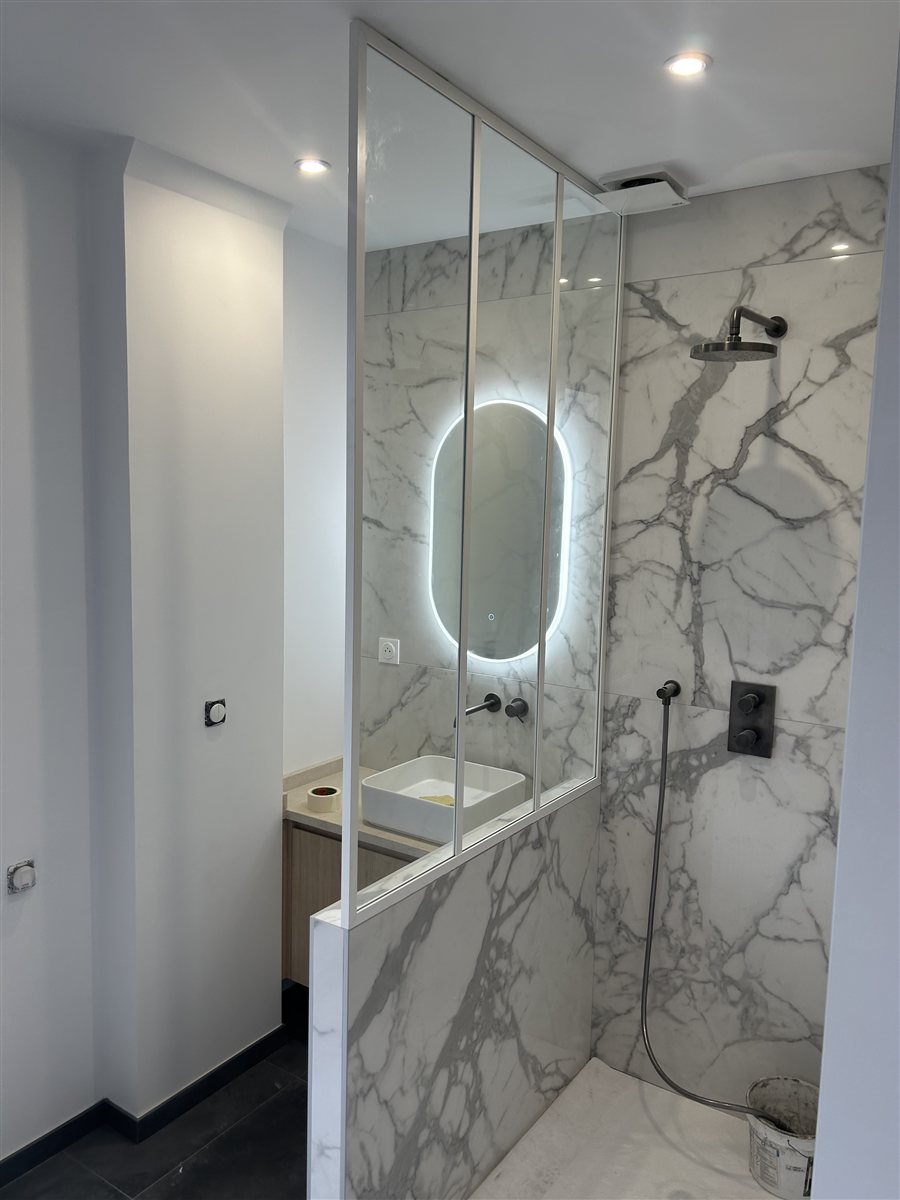 Salle de bain : douche en grand carrelage effet marbre avec verrière et robinetterie
